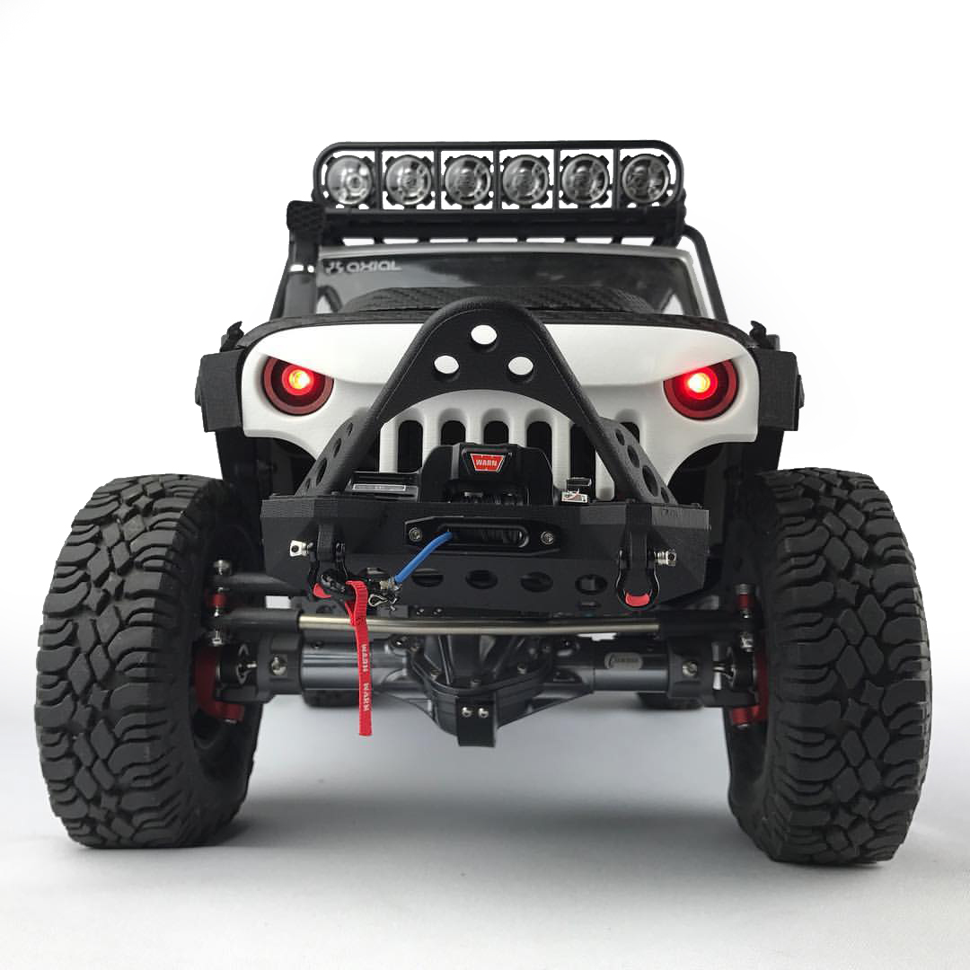 One of the most popular RC cars to upgrade, the Axial SCX10 Jeep® Wrangler Unlimited Rubicon. The image shows the following Knight Customs parts: AJ40011 Halo Light Bucket Set (frosted ultra detail) AJ30006 Skull Face Grill & Mount (White strong & flexible polished) AJ10030 Smittybilt XRC M.O.D. Bumper & Stinger (Stainless Steel) AJ10018 Hood Latch (Black strong & flexible) AJ10023 Smittybilt XRC JK Front Fenders AJ10020 Snorkel Tall (frosted ultra detail) AJ10037 Smittybilt Stingray Hood