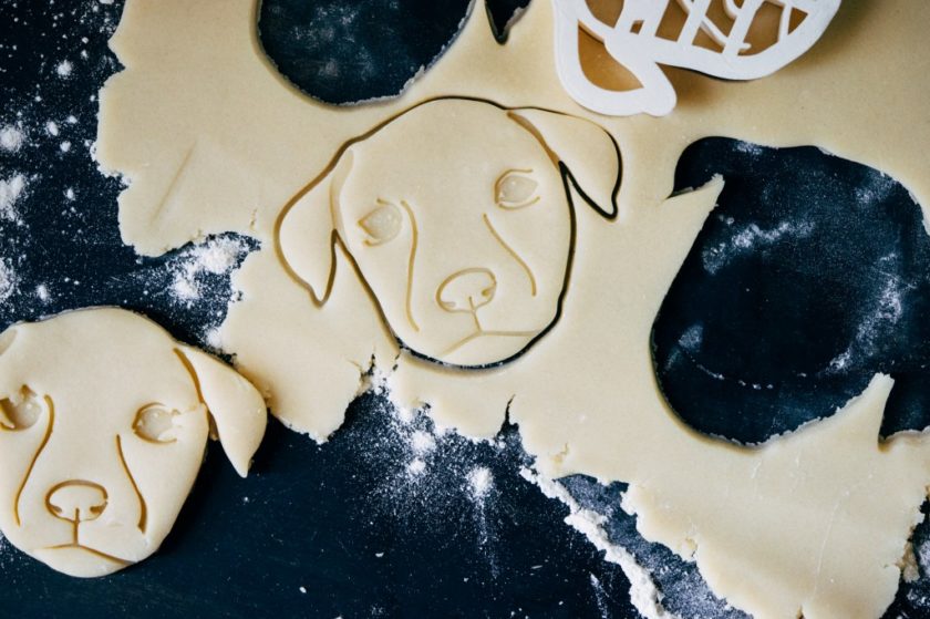 3d printed dog-face cookie cutter sitting on top of dough with imprint of dog face in cookie dough