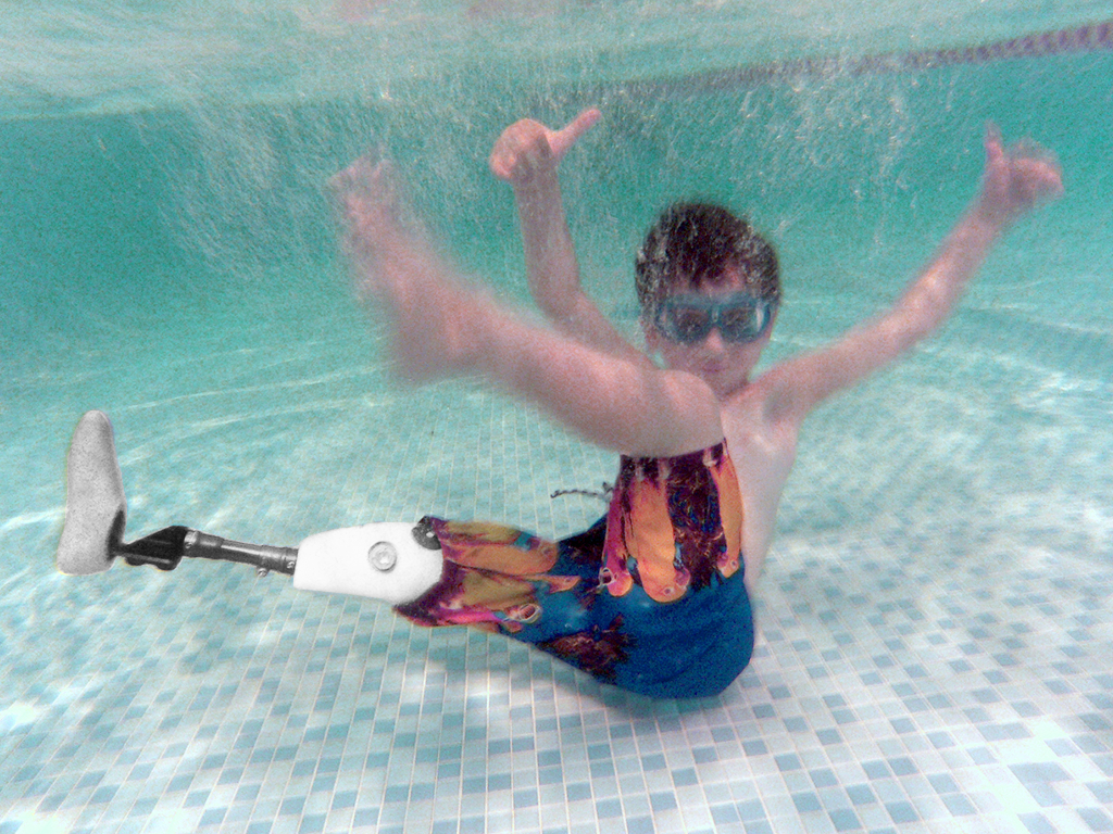 A child swims while wearing a 3D printed prosthetic leg